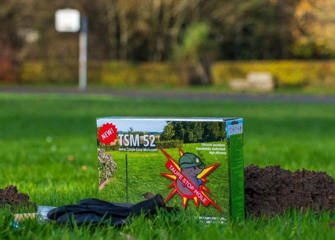 Taupe-Stop-Mole TSM 52 product box in garden lawn near molehill for mole control